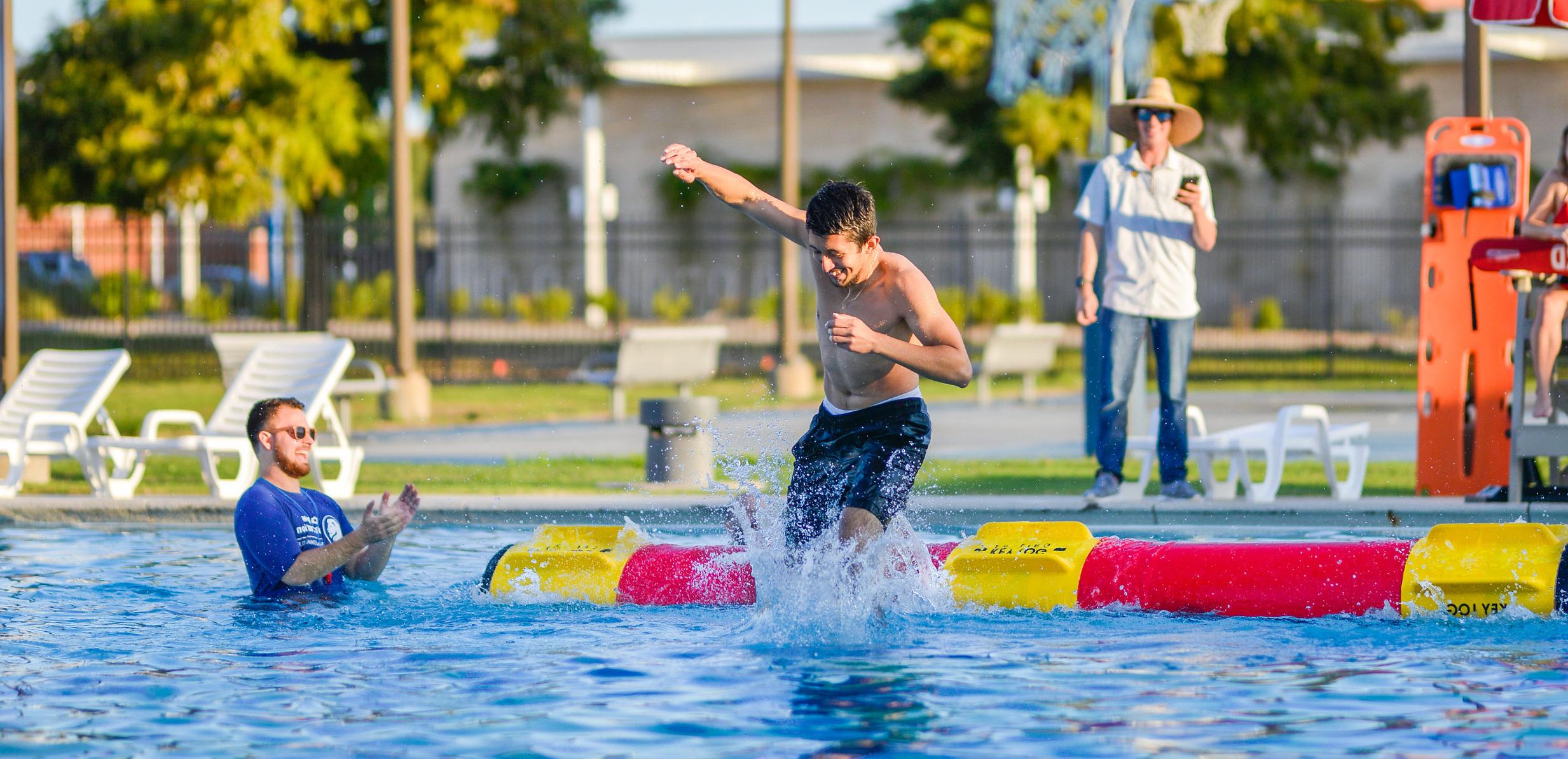 一名学生在校园游泳馆参加滚原木比赛. 